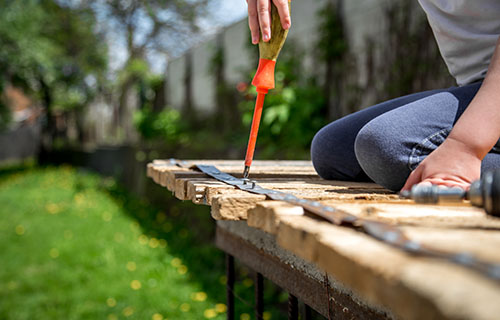 A person skillfully uses a screw driver to construct a wooden bench