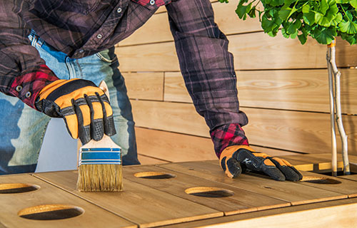 A man carefully paints a wooden table with a brush